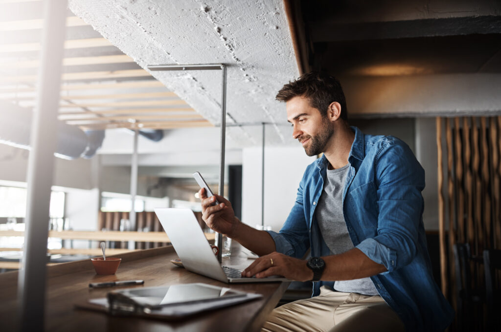 a man sitting at a table looking at a laptop