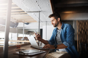 a man sitting at a table looking at a laptop
