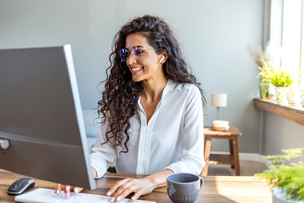 Frau arbeitet im Homeoffice und telefoniert mit kabellosen In-Ear-Kopfhörern.